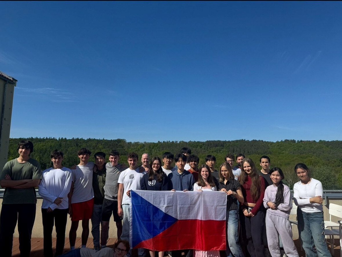 Team Czechia 2025 holding the Czech flag on a terrace above a forest